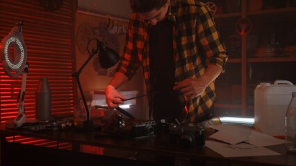 Photographer Developing Film in Dimly Lit Darkroom with Vintage Equipment