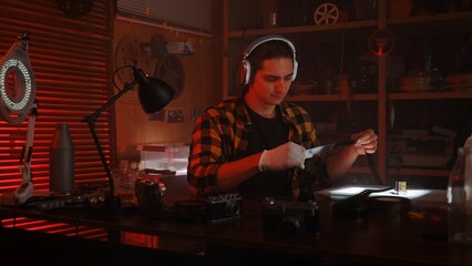 Young Man with Headphones Examining Camera in Retro Photography Studio