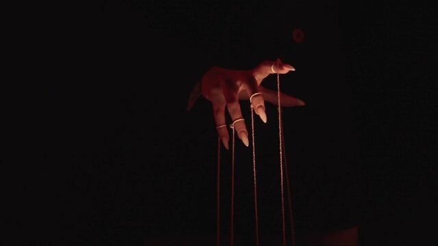Fototapeta Mysterious Hand Pulling Strings in Dim Red Light