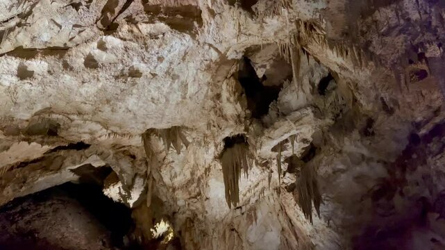 Sharp limestone stalactites hang from textured cave ceiling in dramatic overhead view