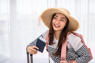 Smiling young Asian woman traveler with passport and boarding pass ready for vacation
