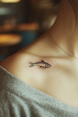 Obraz premium Delicate tattoo of fish on shoulder, blending artistry with coas