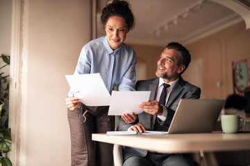 Professional Team Collaborating in Office Environment with Shared Documents and Smiles