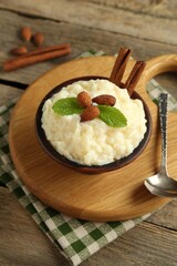 Delicious rice pudding with almonds, mint and cinnamon sticks served on wooden table, closeup