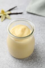 Tasty vanilla pudding, pods and flower on grey table, closeup