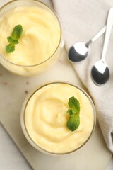 Tasty vanilla pudding with mint served on white wooden table, flat lay