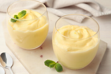 Tasty vanilla pudding with mint served on white wooden table, closeup