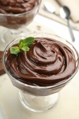 Delicious chocolate pudding with mint in dessert bowl on white table, closeup