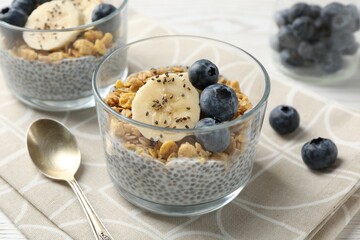 Delicious dessert with chia seeds, yogurt, granola, blueberries and banana on table, closeup. Superfood