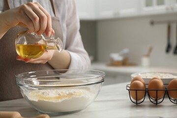 Making khinkali. Woman adding oil into bowl at table in kitchen, closeup