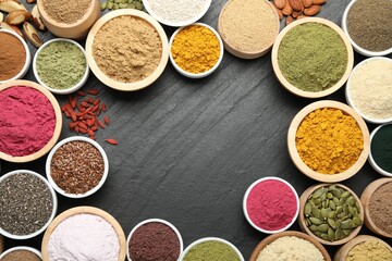 Frame of different superfood powders on black table, flat lay. Space for text
