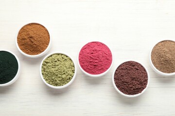 Different superfood powders on white wooden table, flat lay