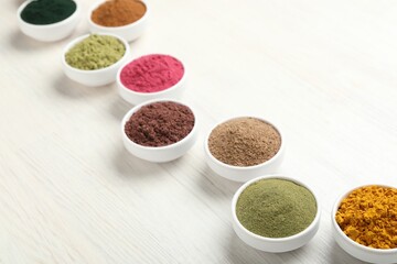 Different superfood powders on white wooden table, closeup