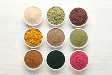 Different superfood powders on white wooden table, flat lay