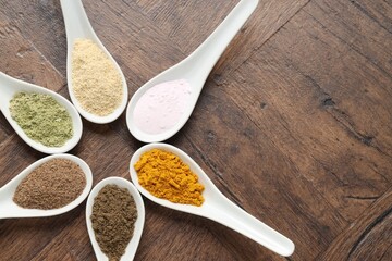 Different superfood powders in spoons on wooden table, flat lay. Space for text