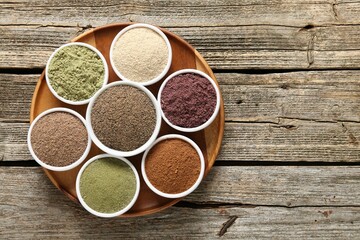 Different superfoods in bowls on wooden table, top view. Space for text