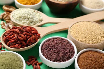 Different superfood products on green background, closeup