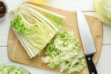 Cut Chinese cabbage and knife on white wooden table, flat lay