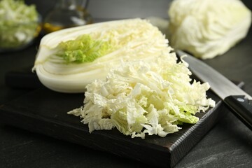 Cut Chinese cabbage and knife on black table, closeup