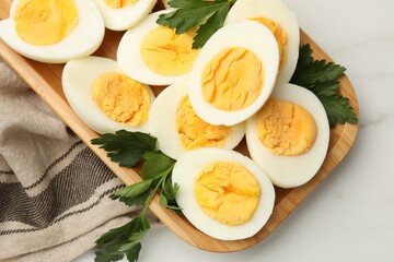 Boiled eggs and parsley on white marble table, top view