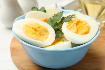 Boiled eggs and parsley in bowl on table, closeup