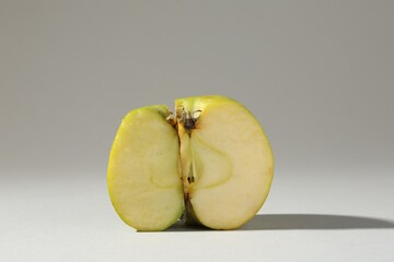 Half of damaged apple on light grey background