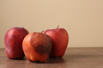 Many rotten red apples on wooden table