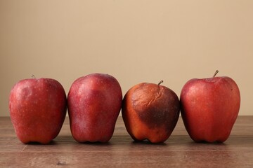Many rotten red apples on wooden table. Space for text