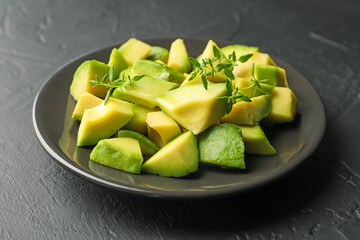 Tasty cut avocados and thyme on black table, closeup