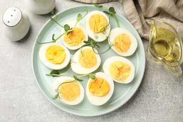 Hard boiled eggs with microgreens on grey table, flat lay