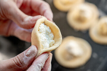 Forming dumplings, close-up of hands at work. Traditional Ukrainian dumplings with cottage cheese - step-by-step process of home cooking.