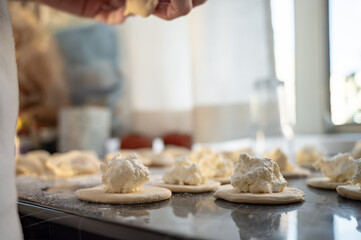 Forming dumplings, close-up of hands at work. Traditional Ukrainian dumplings with cottage cheese - step-by-step process of home cooking.