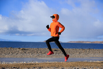 Female runner  running at winter high altitude lakeside, Tibet