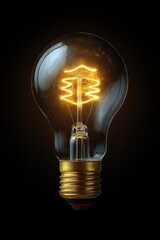 Close-up of a glowing vintage filament light bulb against a black background emitting warm yellow light