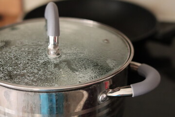 Cooking a pot of water on a stovetop with steam forming under the lid in a kitchen setting