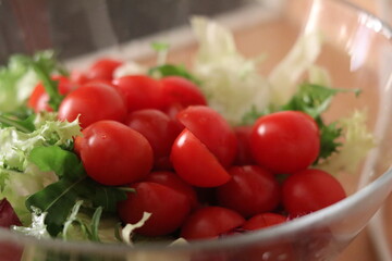 Fresh cherry tomatoes and crisp lettuce in a clear bowl for a healthy salad preparation at home in the kitchen
