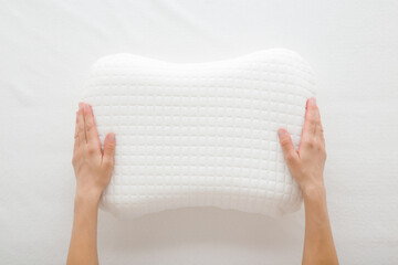 Young adult woman hands holding and showing new soft memory foam pillow with white cover on...