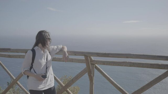 Woman with sunglasses relaxing at scenic wooden lookout over Atlantic Ocean on Madeira island (SLOG3)