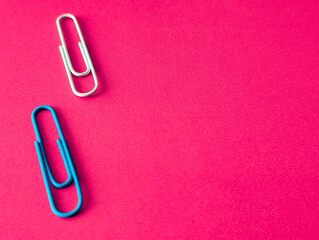 two paper clips on the left side of bright pink background
