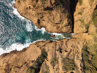 Vue aérienne verticale du haut d'une falaise qui plonge dans la mer