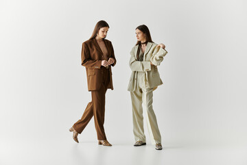 Stylish twin sisters showcase elegant outfits in a modern studio setting during a fashion moment