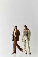 Stylish twin sisters showcase fashion in minimalist studio setting with modern flair