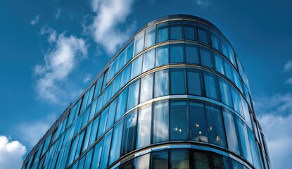 Modern glass office building against a vibrant blue sky.  Curved facade with many windows reflecting the sky