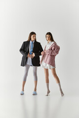 Fototapeta premium Stylish twin sisters showcase unique fashion in an artistic studio setting