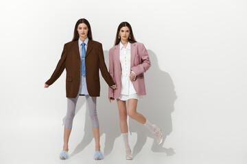 Obraz premium Stylish twin sisters showcasing unique fashion in a modern studio environment