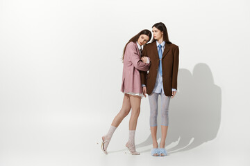 Stylish twins share a tender moment in contemporary fashion studio