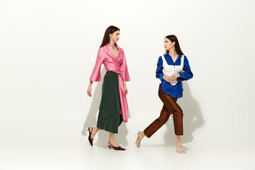 Stylish twin sisters showcase their unique fashion in a contemporary space