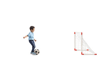 Full length profile shot of an asian boy running with a football and scoring a goal