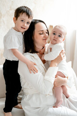 a mother with two children hugs and kisses, maternal love and care, a mother on maternity leave with young children at home, a mother and children