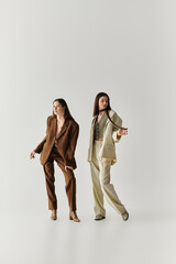 Stylish twin sisters showcase modern fashion elegance in a minimalist setting